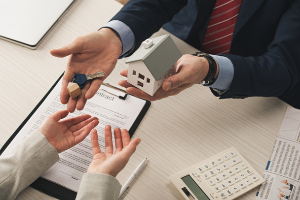 stock photo top view realtor giving keys woman holding carton house model